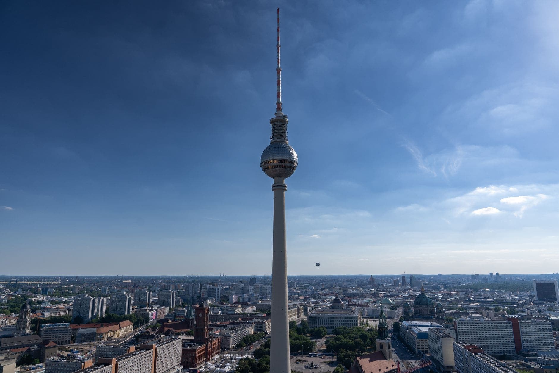 Aerial view of the Berliner Fernsehturm against a blue sky, showcasing Berlin's iconic skyline.