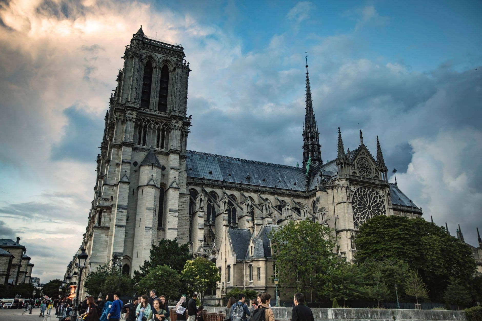 A dramatic shot of Notre Dame Cathedral with people walking by, capturing the architectural elegance.
